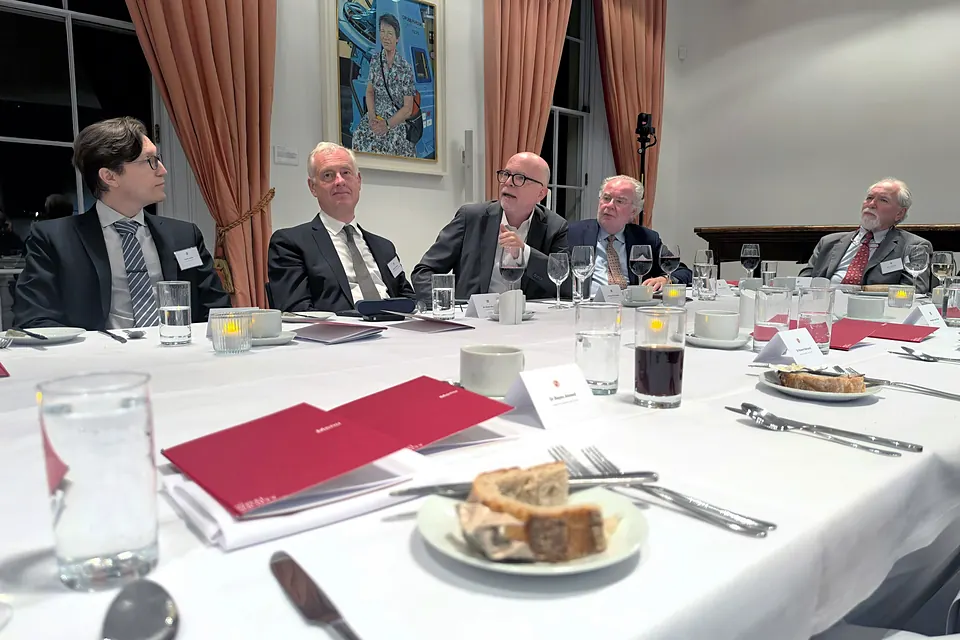 Five guests in conversation at one end of the table, with menus and place cards in the foreground.