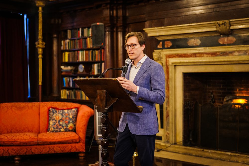 A speaker opens the program from the lectern in the Library